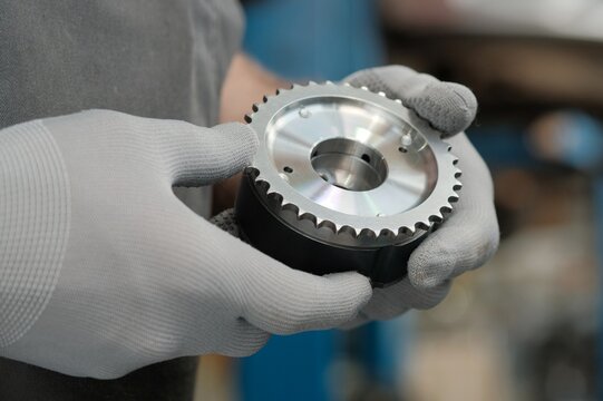 Car service. The car mechanic holds the clutch on the camshaft of the car engine.The VVT phaser.Close-up. Preparation for installation.