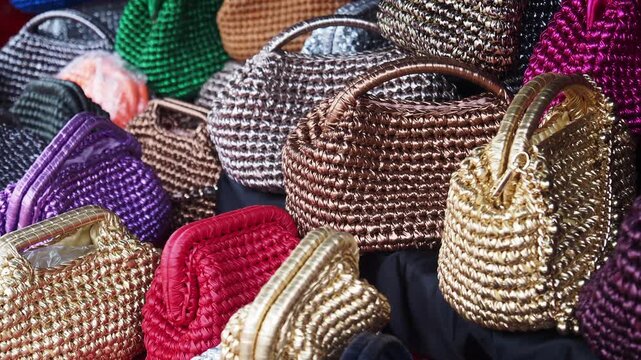 Selection of handmade colorful woven purses and luxury clutch bags displayed at boutique market stall