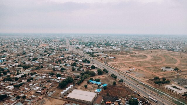 Farawa, Nigeria - 17 June 2026: Aerial view of the urban landscape with a major road dividing residential areas and open development plots under an overcast sky.