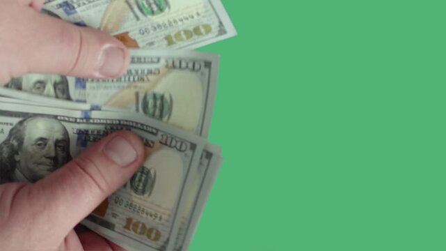 Man hands over dollar bills in a simple exchange for cash on a green background