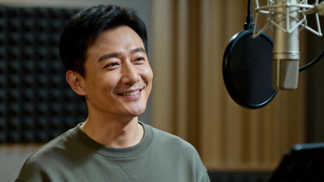 Smiling asian male voice actor recording studio microphone soundproof wall portrait