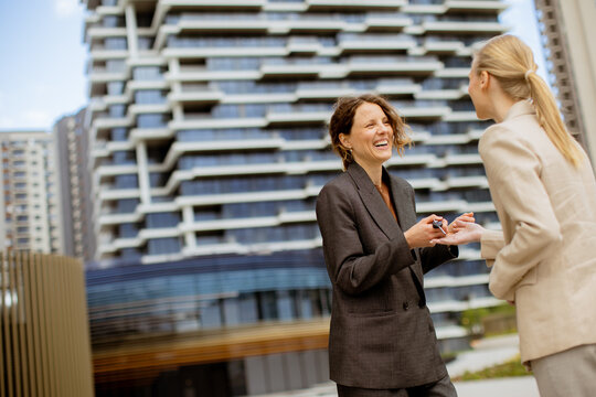 Business meeting between two women outside a modern building on a sunny day