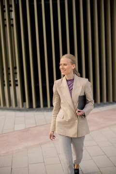 Woman walks in business outfit near modern building during daytime in city