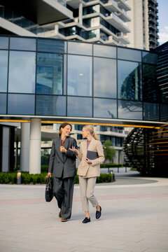 Colleagues chat and walk outside a modern building in the city during the day