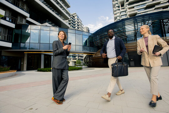 Business professionals walking in urban area during daytime near modern buildings