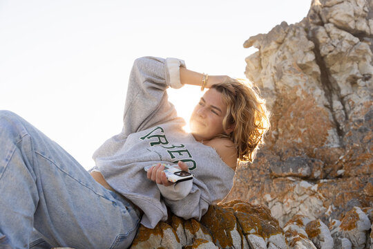 young woman resting on rock with sun hitting her hair
