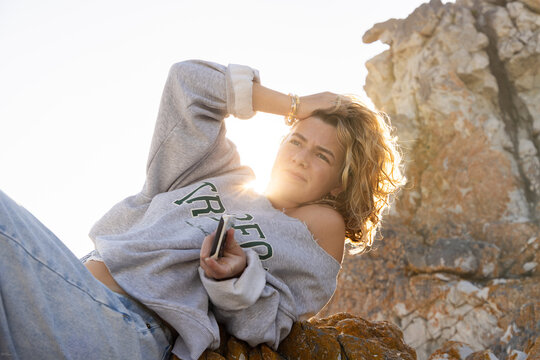 young woman resting on rock with sun hitting her hair