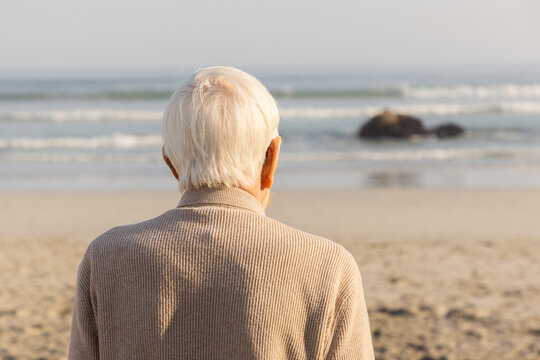 rear view of elderly man looking out at ocean waves, grotto beach, hermanus, South Africa