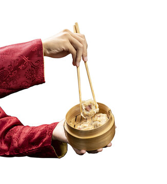 Chinese person with chopstick eating dim sum dumpling on bamboo wooden basket bowl
