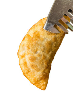Crispy golden fried dumpling held by metal tongs, isolated