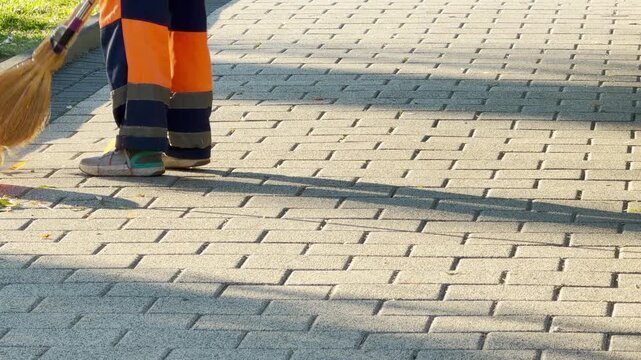 A proud street cleaner sweeps a paved walkway during a peaceful morning. This diligent care brings a fresh, hopeful feeling to Simferopol, Crimea.