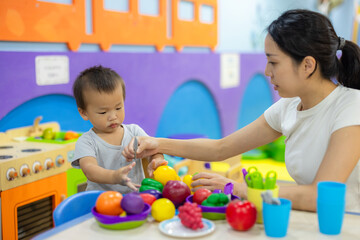 Obraz premium Mother and son playing with toy food in classroom