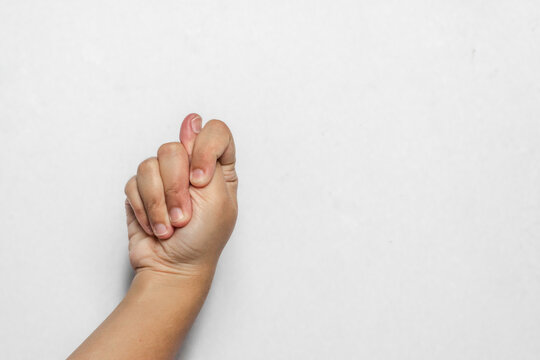 An Asian woman's hand showing a fig sign or lucky gesture on a white background. Concept of protection, hope, and a traditional hand symbol.