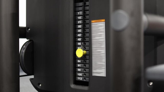 Athlete hesitates while adjusting weight on a gym machine trying to choose the right resistance level for training progression strength goals and effective exercise