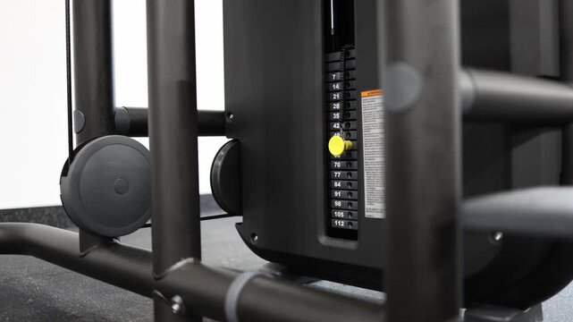 Close up of gym cable machine weight stack set to medium resistance level during workout preparation showing adjustable load selection for strength and fitness training