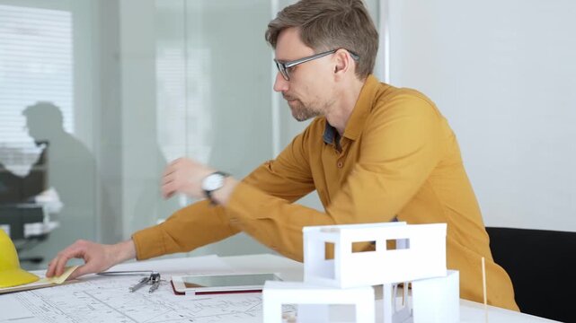 Professional architect designing a new building project, planning with blueprints and a scale model in a modern office, developing urban structures and innovative construction ideas