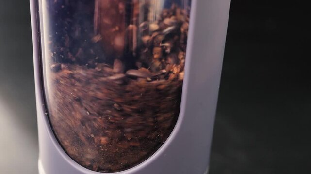 A macro close-up image of roasted coffee beans in a coffee machine or grinder hopper, highlighting rich textures, warm tones, and a shallow depth of field.