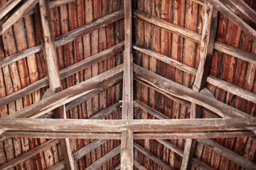 An intricate network of wooden beams and planks used to support a roof © Redzen
