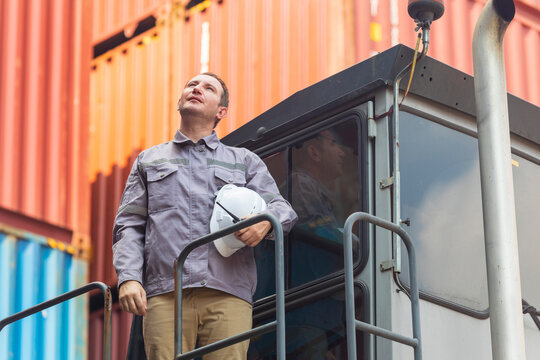 American engineer in uniform holding hard hat standing in containers yard, worker tired of frustration. 