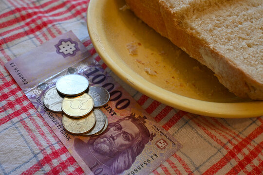 Close-up of bread on a plate next to Hungarian forint money, representing cost of living crisis and basic food affordability.