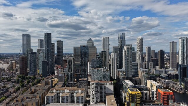 London, United Kingdom - 16 June 2026: Aerial view of the modern skyscrapers of Canary Wharf financial district under a cloudy blue sky.