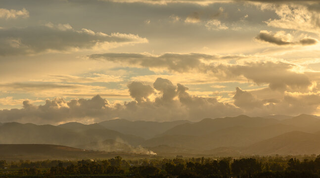 Golden hour casts a warm glow over the tranquil mountains and rolling landscape
