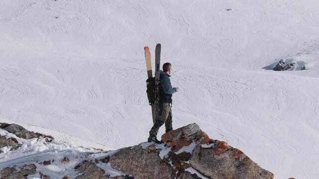  4K 59.94fps Cinematic drone orbit around a ski mountaineer on a rocky summit in Flims Laax, Swiss Alps, surrounded by rugged alpine terrain and snow-covered peaks.