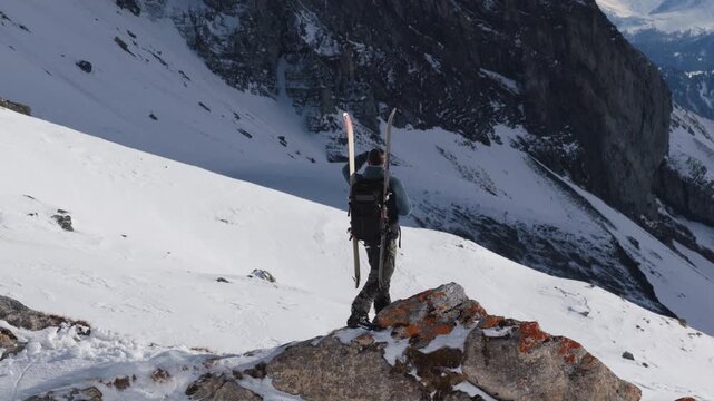  4K 59.94fps Cinematic drone orbit around a ski mountaineer on a rocky summit in Flims Laax, Swiss Alps, surrounded by rugged alpine terrain and snow-covered peaks.