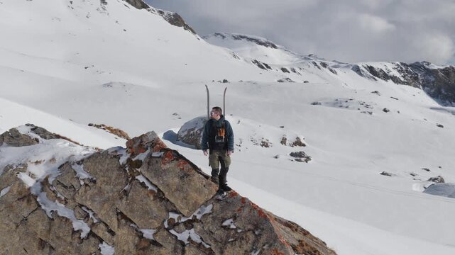  4K 59.94fps Cinematic drone orbit around a ski mountaineer on a rocky summit in Flims Laax, Swiss Alps, surrounded by rugged alpine terrain and snow-covered peaks.