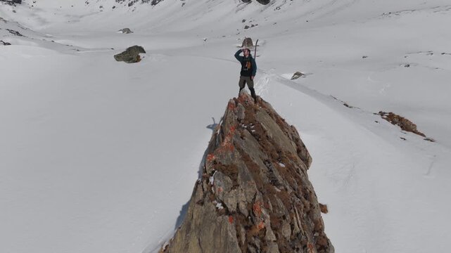  4K 59.94fps Cinematic drone orbit around a ski mountaineer on a rocky summit in Flims Laax, Swiss Alps, surrounded by rugged alpine terrain and snow-covered peaks.