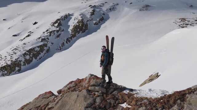  4K 59.94fps Cinematic drone orbit around a ski mountaineer on a rocky summit in Flims Laax, Swiss Alps, surrounded by rugged alpine terrain and snow-covered peaks.