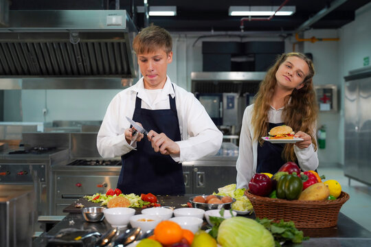 Group children girl and boy leaning and cut vegetables for cooking food.  Chef teacher teaches cooking to the group children in class kitchen room.  Chef preparing student for learning marking food