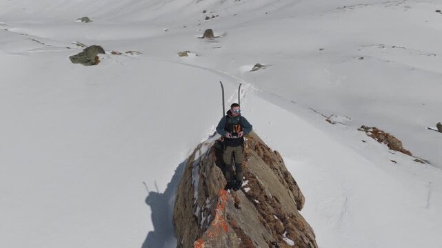  4K 59.94fps Cinematic drone orbit around a ski mountaineer on a rocky summit in Flims Laax, Swiss Alps, surrounded by rugged alpine terrain and snow-covered peaks.
