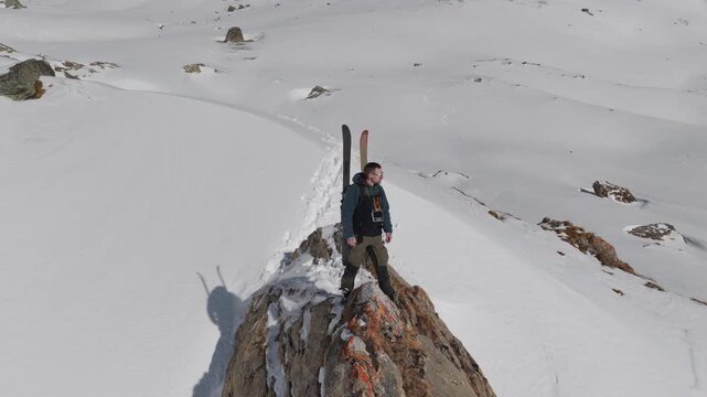  4K 59.94fps Cinematic drone orbit around a ski mountaineer on a rocky summit in Flims Laax, Swiss Alps, surrounded by rugged alpine terrain and snow-covered peaks.