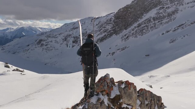  4K 59.94fps Cinematic drone orbit around a ski mountaineer on a rocky summit in Flims Laax, Swiss Alps, surrounded by rugged alpine terrain and snow-covered peaks.
