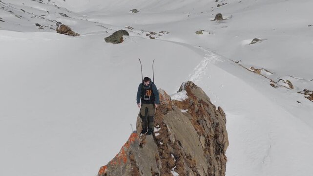  4K 59.94fps Cinematic drone orbit around a ski mountaineer on a rocky summit in Flims Laax, Swiss Alps, surrounded by rugged alpine terrain and snow-covered peaks.