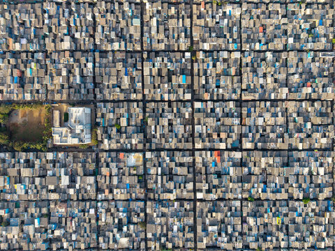 Aerial view of the dense urban settlement of Malvani, featuring a grid of tightly packed rooftops and narrow alleyways in Mumbai, Maharashtra, India.