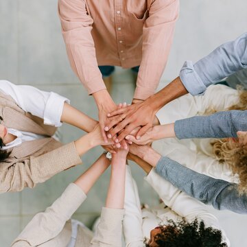 Multiethnic business group stacking hands in a circle for a teamwork and unity concept, viewed from an overhead perspective with soft lighting