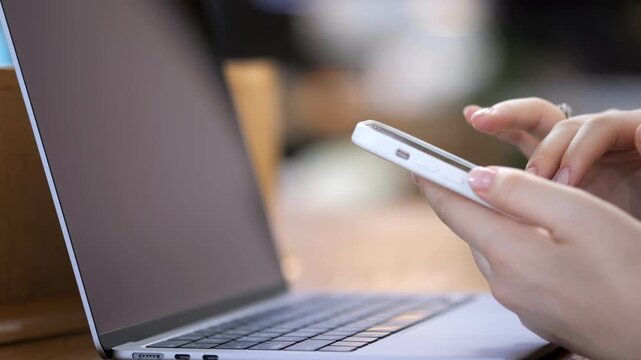 Person multitasks with phone and laptop. Focused on digital devices. Ideal for work, communication, or tech themes