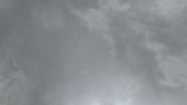 A dense canopy of heavy, slate-gray storm clouds fills the frame. The churning, monochromatic textures suggest an impending downpour, capturing a somber, restless atmosphere beneath a turbulent sky.