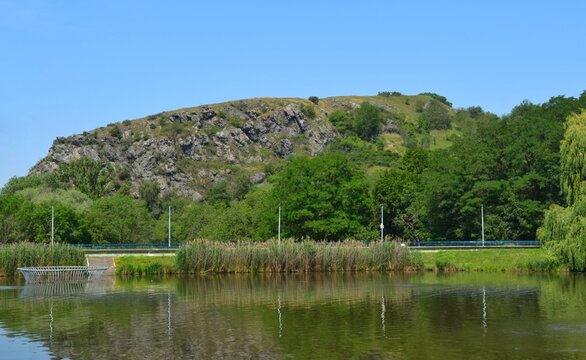 Scenic summer landscape of Dzban lake with rocky hills and green trees reflection in water, Divoka Sarka park in Prague