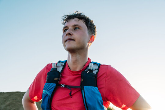 Trail runner contemplating challenge wearing hydration pack