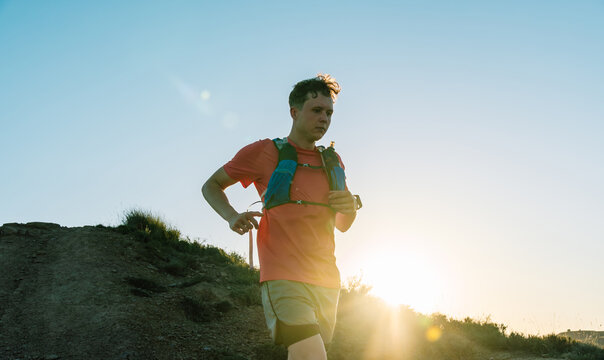 Man trail running on hill at sunset