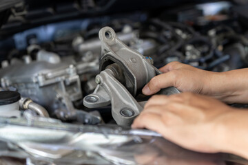 Naklejka na ściany i meble Close up mechanic holding worn engine mount part while inspecting car engine bay, Replacing damaged automotive components according to service schedule, Vehicle maintenance, Safety check optimal