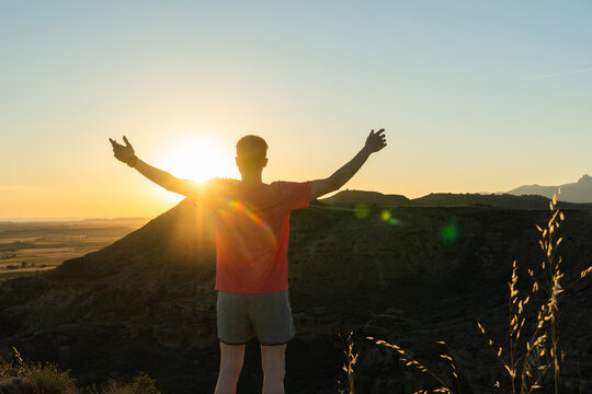 Person with arms outstretched feeling freedom at sunset