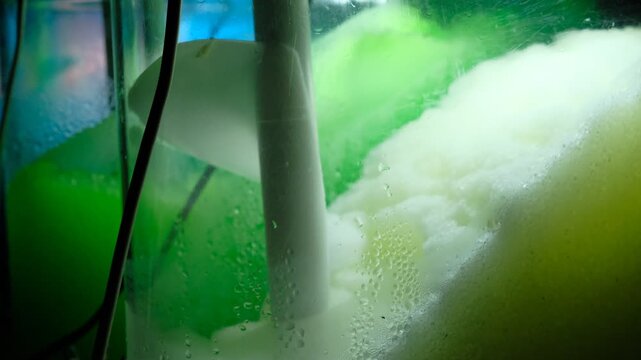 Ice cold sorbet machine mixing fruit juice. Freezing slush spinning around, summer treat. Crushed iced coloured with fruit flavor sweeteners 