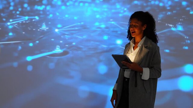 Female IT developers stand talking explaining how to use a data management system, business intelligence, data statistics, marketing analysis, and behind a slide on a conference room screen.