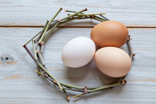 A bunch of asparagus and three eggs on a wooden surface