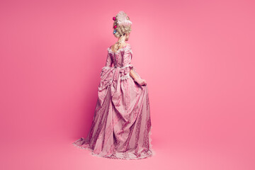 Back view photo of lady princess wearing antique style dress standing back isolated pink color background © deagreez