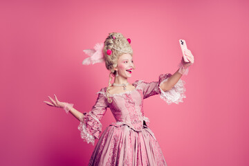 Fototapeta premium Photo of excited beautiful aristocrat lady queen recording video isolated on pink color background
